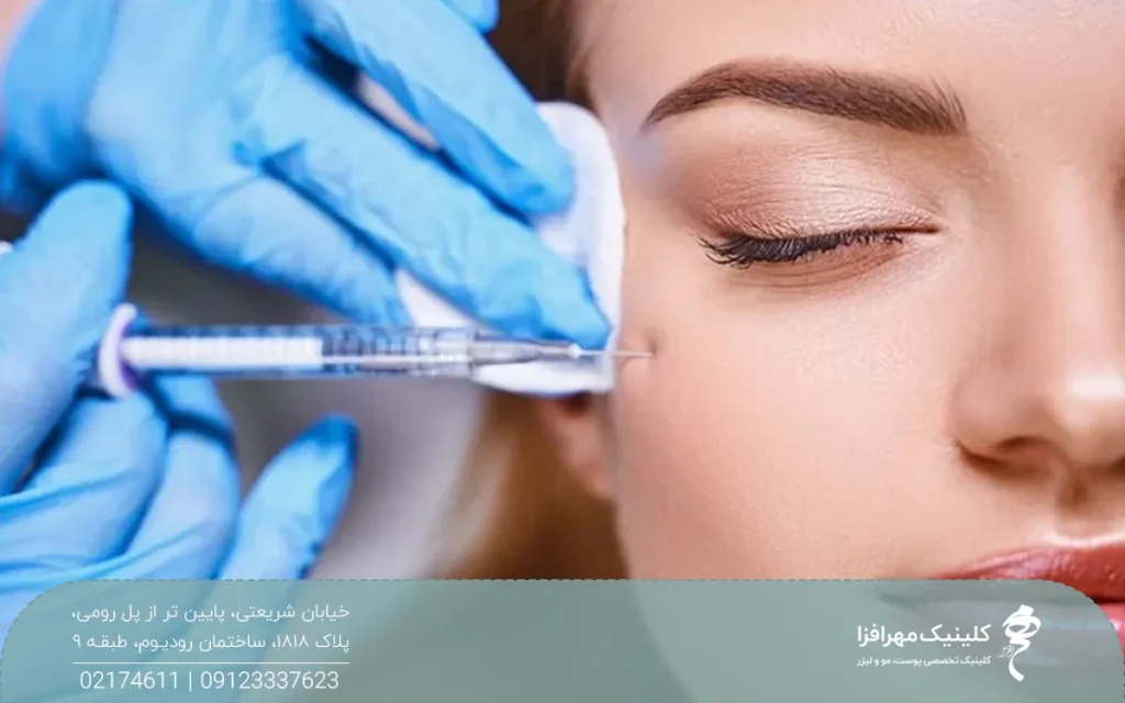 دستان دکتری که دستکش آبی دارد و در حال ژل زدن به گونه صورت فرد است